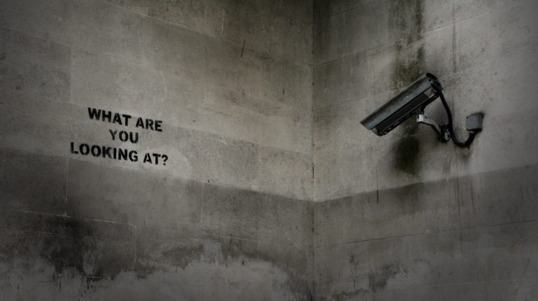 Überwachungskamera mit dem Graffiti „WHAT ARE YOU LOOKING AT?“
